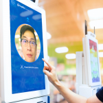 a young man touching a large screen with his face on it